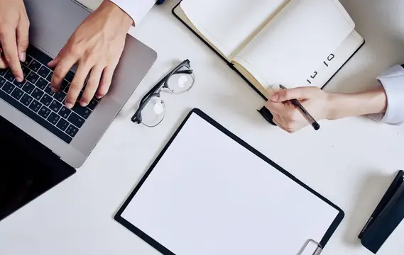 Руки деловых людей за работой с ноутбуком и блокнотом