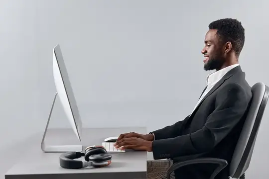 Темнокожий мужчина в деловом костюме работает за компьютером в офисе