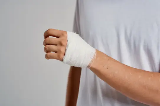 Забинтованное запястье мужчины на сером фоне