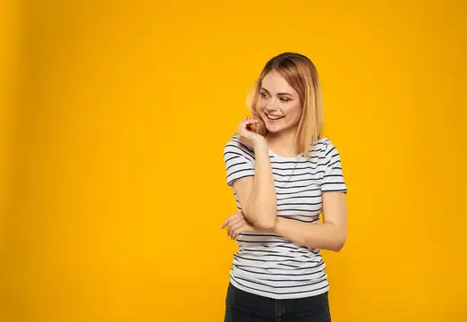 Счастливая блондинка с закрытыми глазами на жёлтом фоне