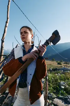 Женщина-фермер держит лопату и мотыгу на склоне холма в сельской местности, работа на открытом воздухе в сельском хозяйстве с инструментом для копания почвы, уход за садом или виноградником на фоне…