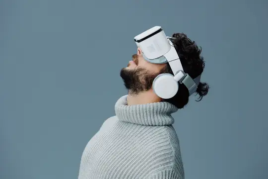 Бородатый мужчина в VR-очках и наушниках смотрит вверх