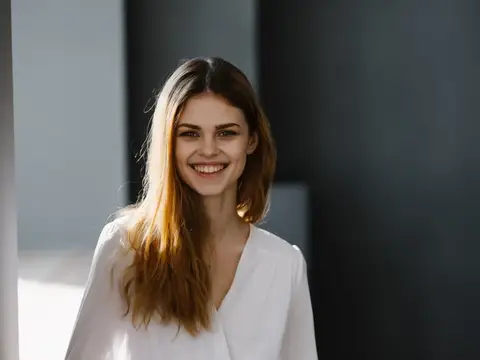 Улыбающаяся молодая женщина с длинными волосами в белой блузке