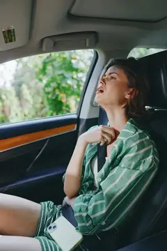 Уставшая темноволосая женщина откинулась на сиденье автомобиля