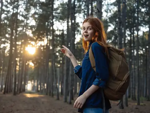 Рыжеволосая женщина с телефоном в руках в лесу, веселое путешествие