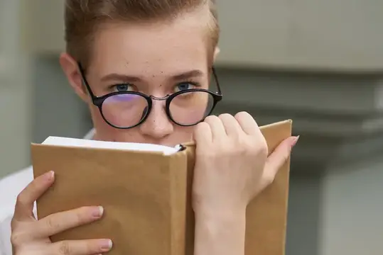 Симпатичная женщина в очках гуляет по городу с книгой, общаясь с окружающими