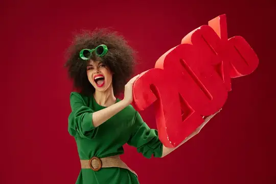 Кудрявая девушка в зелёном платье держит красную надпись SALE