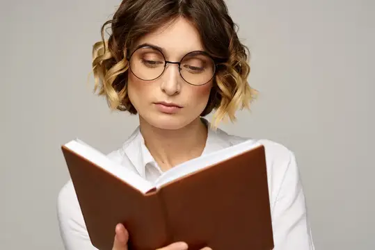 Молодая женщина в очках с книгой в руках