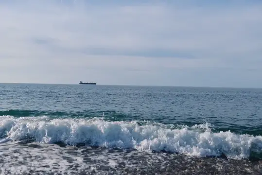 Одинокий грузовой корабль на горизонте спокойного моря