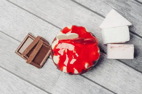 Пирожное с клубничным джемом и кусочки шоколада на серых досках