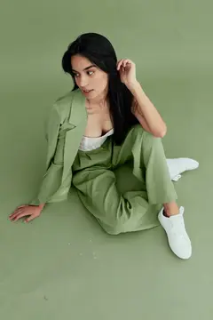 Молодая брюнетка в зелёном костюме сидит на полу