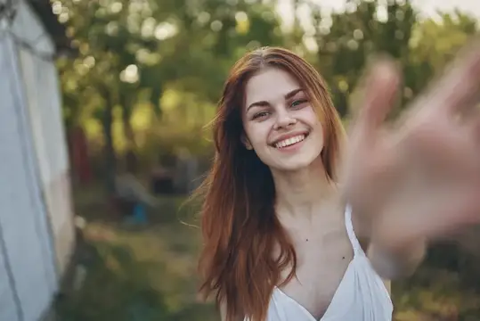 Счастливая женщина жестикулирует руками на открытом воздухе в саду, лето, деревья, отдых