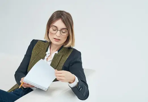 Молодая женщина в очках с блокнотом и карандашом на белом фоне