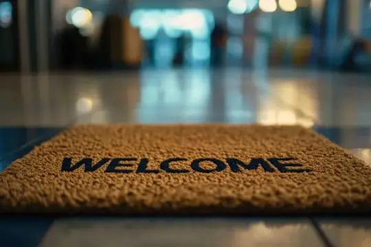 Коричневый коврик с надписью Welcome на полу в размытом холле
