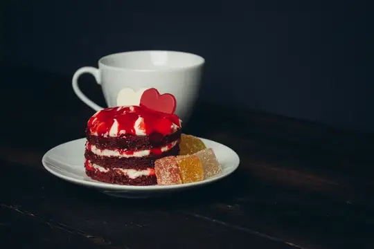 Красный бархатный торт с мармеладом и чашка кофе на тёмном столе