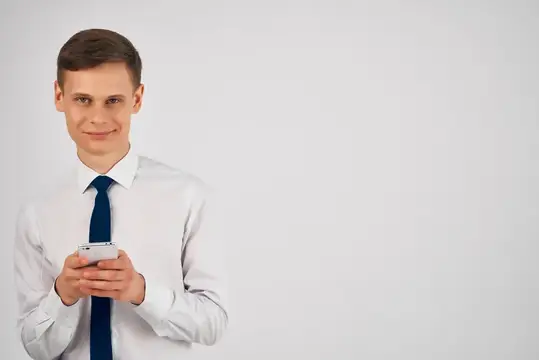 Молодой человек в белой рубашке с телефоном на сером фоне