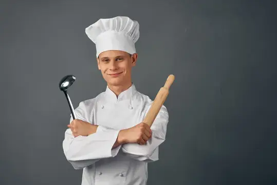 Улыбающийся повар в колпаке с половником и скалкой