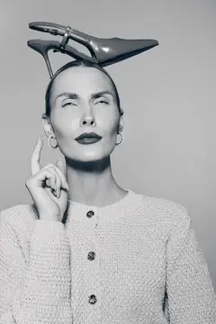 Строгая женщина с туфлей на голове в студии