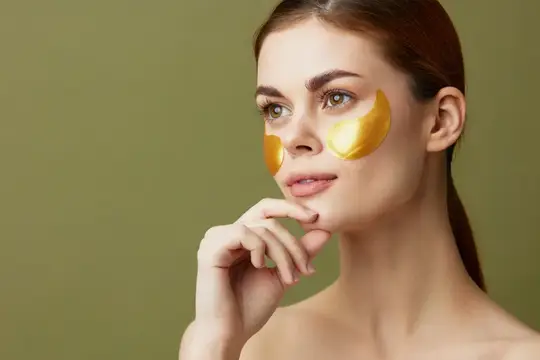 Молодая женщина с золотыми патчами под глазами на оливковом фоне