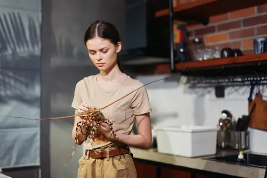 Молодая женщина держит живого лангуста на кухне