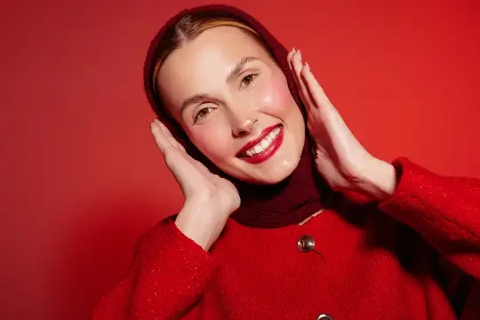 Улыбающаяся девушка в красном капюшоне на красном фоне