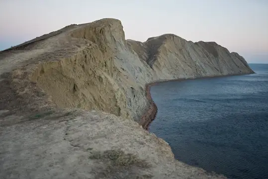 Обрывистый скалистый берег и спокойное море в сумерках