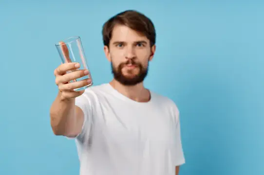 Счастливый мужчина со стаканом воды на синем фоне
