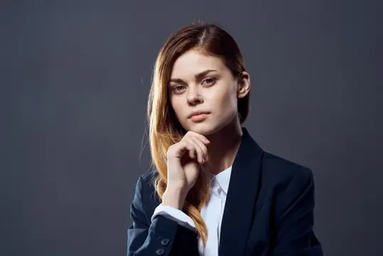 Задумчивая молодая женщина в деловом костюме на сером фоне