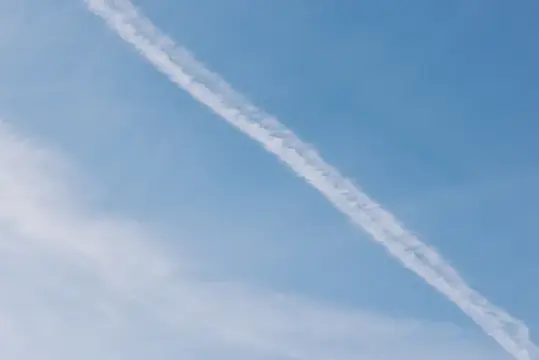 Белый инверсионный след самолёта на ясном голубом небе