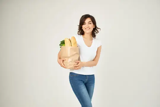 Весёлая женщина с бумажным пакетом продуктов, овощей и доставкой