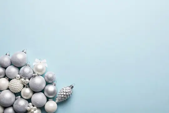 Серебристые ёлочные шары и шишка на голубом фоне