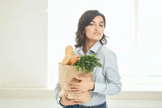 Женщина с пакетом продуктов на кухне