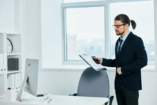 Офисный работник в очках, излучающий уверенность в себе, работает на руководящей должности