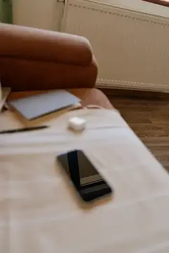 Смартфон и наушники лежат на кровати в спальне
