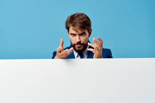 Эмоциональный мужчина с белым рекламным щитом, копи-спейс, синий фон