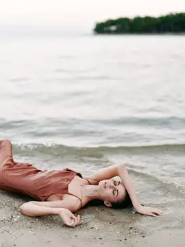Молодая женщина лежит на песке у кромки воды