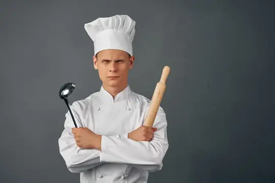 Мужчина в форме шеф-повара на фоне кухонной техники в профессиональном ресторане