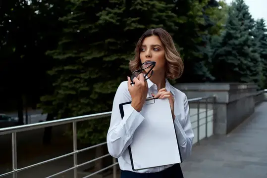 Женщина в деловом костюме на открытом воздухе с документами в руках на светлом фоне