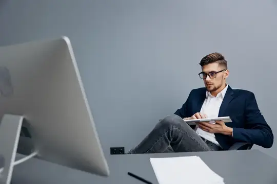 Молодой мужчина в очках работает за компьютером в офисе