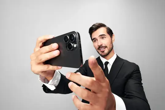 Улыбающийся мужчина в костюме делает селфи на смартфон
