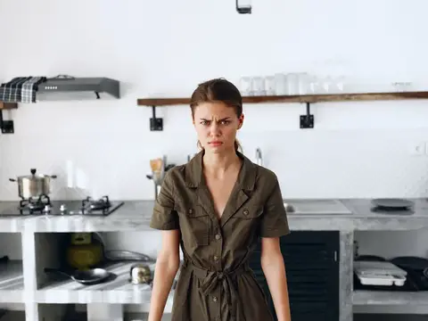 Недовольная женщина в платье хмурится на кухне
