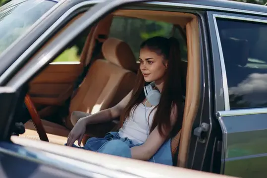 Молодая темноволосая девушка сидит в салоне автомобиля