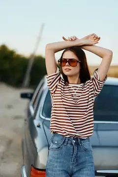 Молодая женщина в солнечных очках отдыхает у машины на дороге