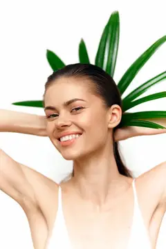 Улыбающаяся девушка с зелеными листьями за головой