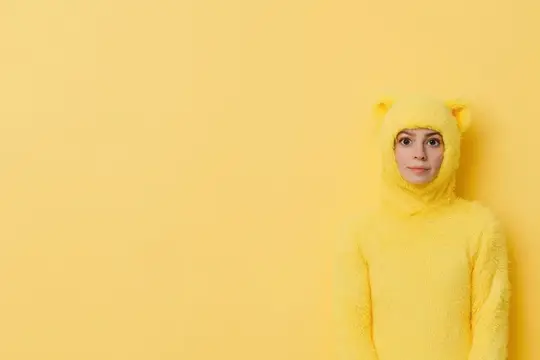 Молодая женщина в жёлтом костюме кошки на жёлтом фоне