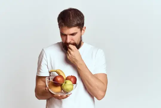 Задумчивый бородатый мужчина с миской фруктов