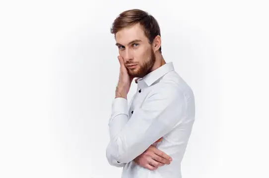 Задумчивый бородатый мужчина в белой рубашке на белом фоне