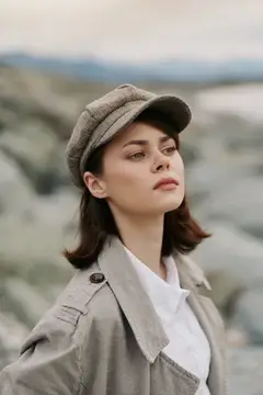 Молодая женщина в кепке и плаще на фоне скал