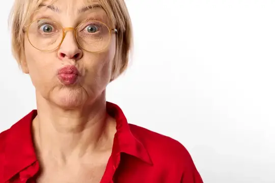 Крупный план портрета удивлённой женщины в красной рубашке, широко раскрытые глаза и поджатые губы, на лице очки