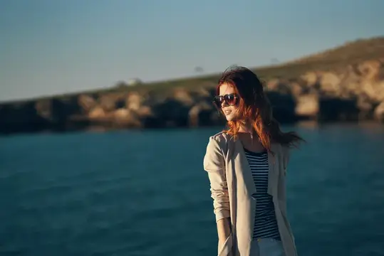 Модель в очках, женщина идет по пляжу у моря, вид сбоку